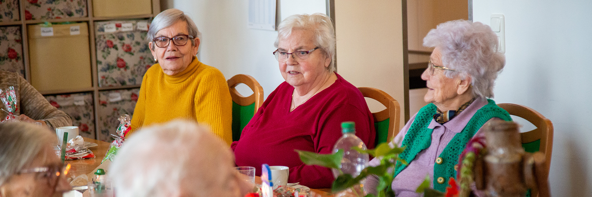 Drei Seniorinnen am Tisch die sich unterhalten.