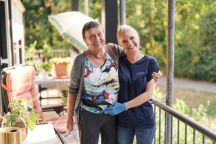 Pflegerin und Bewohnerin auf dem Balkon ihres Zimmers