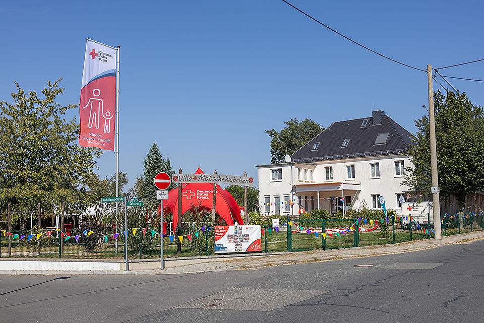 Spielende Kinder und Erwachsene bei einer Festrede auf dem Gelände des Kinderhaus "Villa Motschekiebchen" Falkenhain