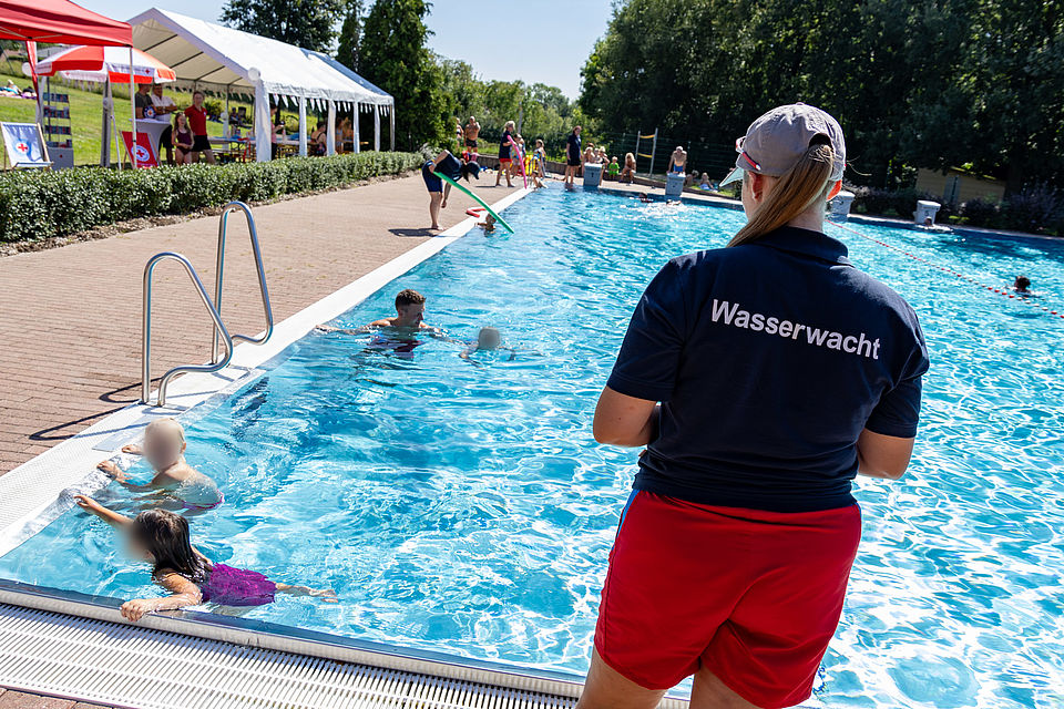 Ein Foto aus dem Freibad Burkartshain, welches Mitglieder der Wasserwacht im Training zeigt oder bei Festreden.
