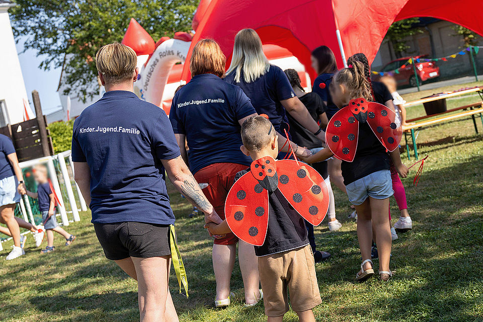 Spielende Kinder und Erwachsene bei einer Festrede auf dem Gelände des Kinderhaus "Villa Motschekiebchen" Falkenhain