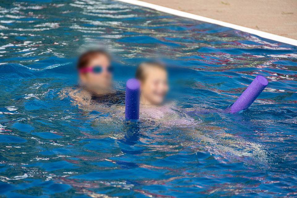 Ein Foto aus dem Freibad Burkartshain, welches Mitglieder der Wasserwacht im Training zeigt oder bei Festreden.