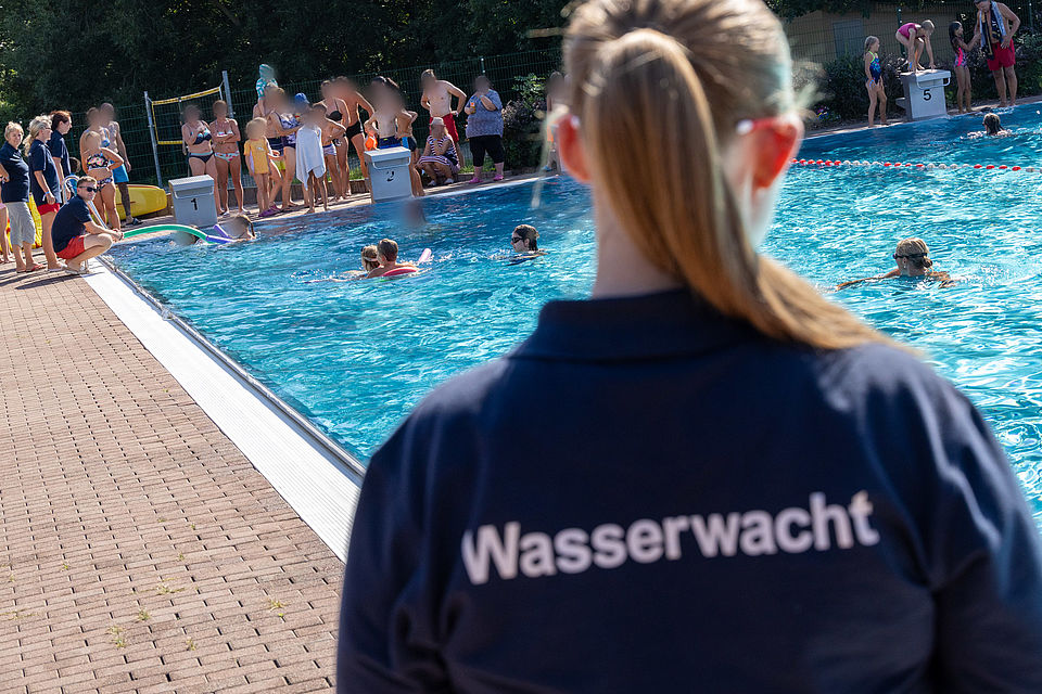 Ein Foto aus dem Freibad Burkartshain, welches Mitglieder der Wasserwacht im Training zeigt oder bei Festreden.