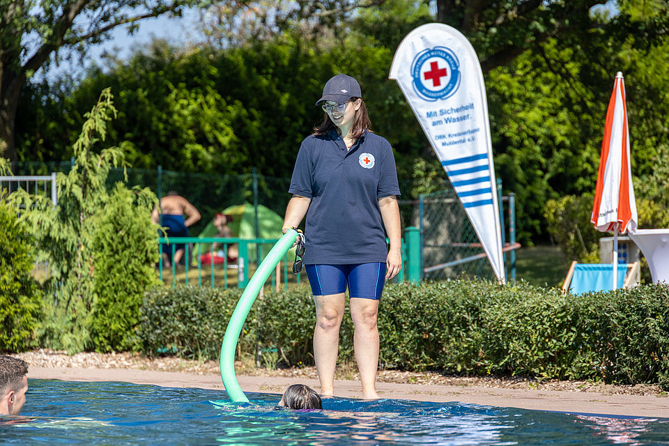 Ein Foto aus dem Freibad Burkartshain, welches Mitglieder der Wasserwacht im Training zeigt oder bei Festreden.