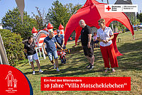 Spielende Kinder und Erwachsene bei einer Festrede auf dem Gelände des Kinderhaus "Villa Motschekiebchen" Falkenhain