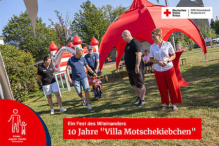 Spielende Kinder und Erwachsene bei einer Festrede auf dem Gelände des Kinderhaus "Villa Motschekiebchen" Falkenhain