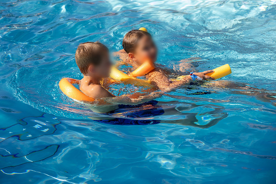 Ein Foto aus dem Freibad Burkartshain, welches Mitglieder der Wasserwacht im Training zeigt oder bei Festreden.