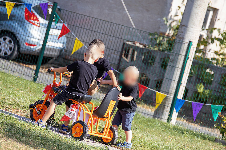 Spielende Kinder und Erwachsene bei einer Festrede auf dem Gelände des Kinderhaus "Villa Motschekiebchen" Falkenhain