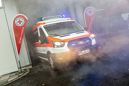Ein Fharzeug im künstlichen nebel, der aus einem Hallentor fährt.